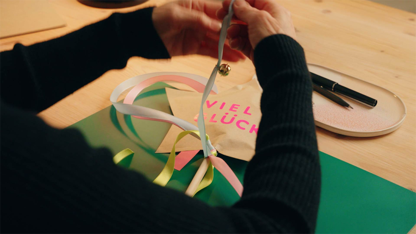 Bunte Satinschleifen werden an einen Holzstiel mit einem Stern aus Kraftpapier gebunden - WestLotto DIY-Idee