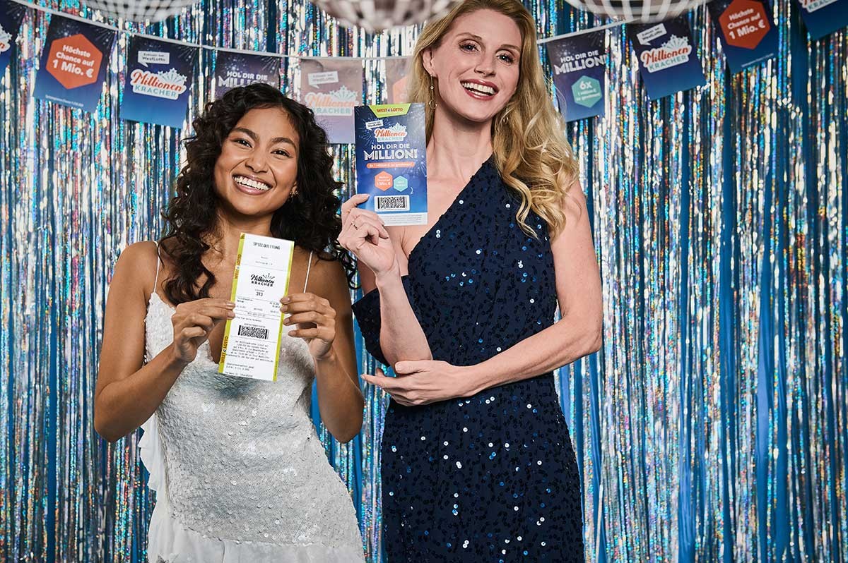 Zwei Frauen halten ein MillionenKracher-Los hoch und freuen sich - WestLotto