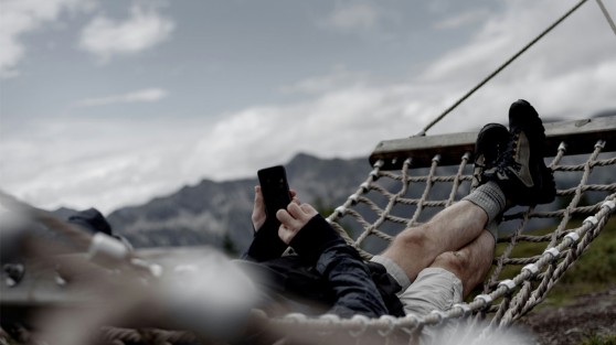 Person liegt in einer Hängematte in den Bergen und bedient sein Smartphone