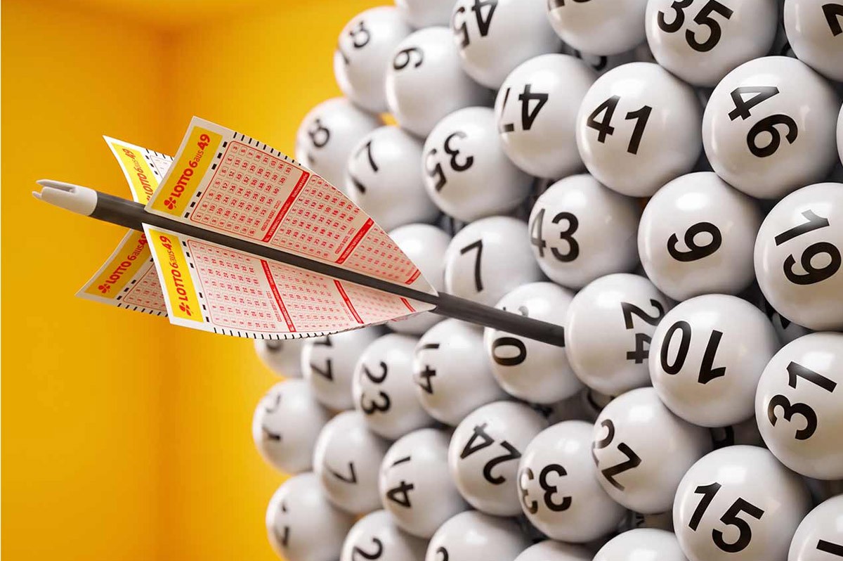 Ein Dartpfeil aus einem Lotto.Schein trifft in eine Sammlung aus zahlreichen Lottozahlen - WestLotto