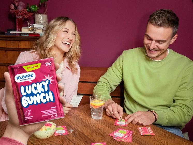 Pärchen sitzt an Esstisch, spielt Rubbelquiz Lucky Bunch und freut sich - WestLotto