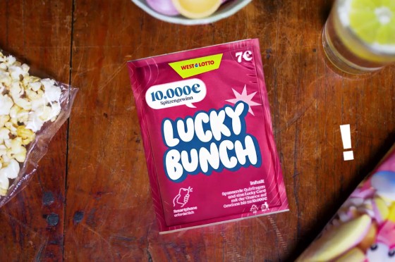 WestLotto-Rubbelquiz Lucky Bunch liegt auf dunklem Holztisch. Daneben Süßigkeiten.