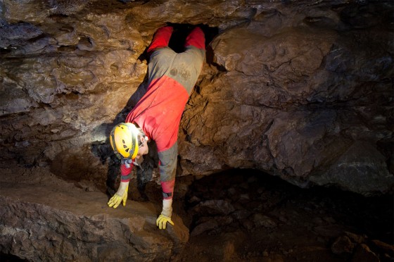 Mensch mit Helm klettert aus einem Loch in einer Höhle | Ausflugsort NRW