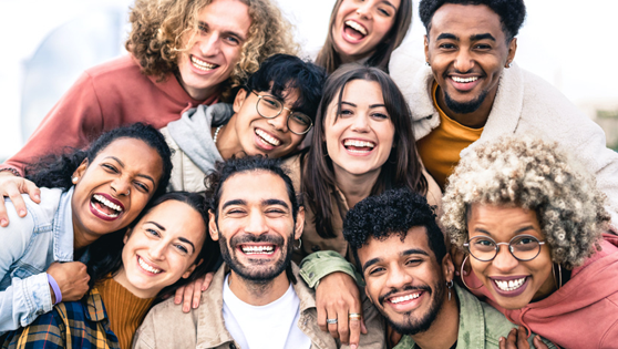 Viele Menschen unterscheidlichen Geschlechts, Alters und Herkunft lachen in die Kamera